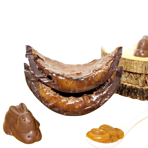 Two pieces of chocolate stacked next to a spoonful of caramel spread and a chocolate bunny.