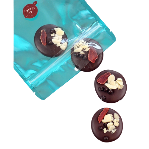 Cyan pouch with 4 dark chocolate disks coming out of it topped with dried strawberry almond and dark chocolate balls 