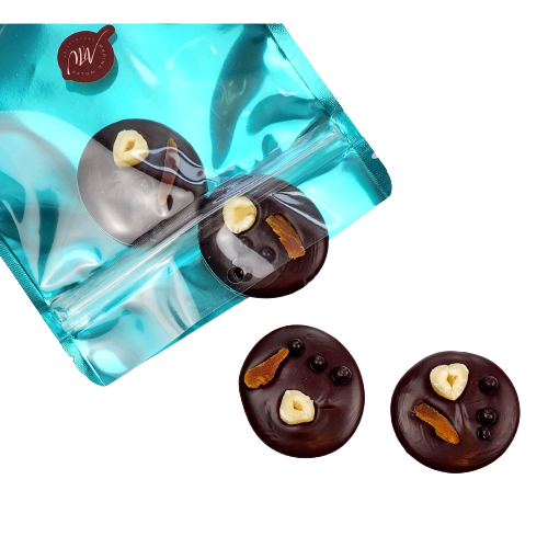 Cyan pouch with 4 dark chocolate disks topped with slice of apricot, hazelnut, and dark chocolate balls