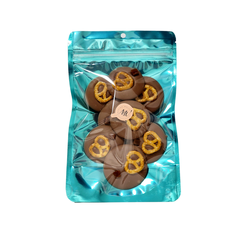 Cyan stand-up pouch with 8 milk chocolate disks topped with pretzel and a piece of caramel