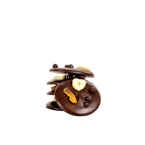 A pile of 5 dark chocolate disks topped with a slice of apricot, hazelnut, and dark chocolate balls