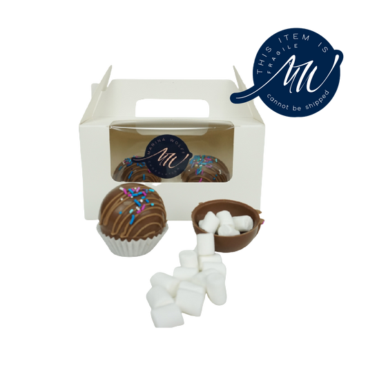 White box with chocolate and 1 chocolate sphere and 1 half-sphere with mini-marshmallows in it with a label that says 'this item is fragile cannot be shipped'